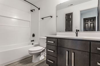 A white toilet sits in a bathroom with a wooden vanity and a large mirror